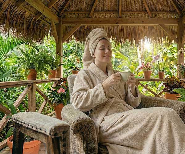 Une personne enveloppée dans des linges blancs épais après le modelage, buvant un thé